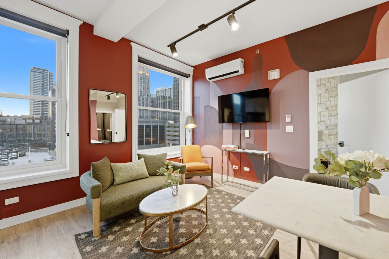 Red mural living room with green sofa, city views, and dining area